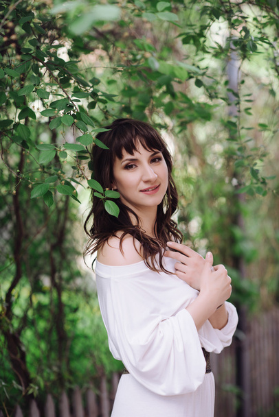 Portrait of a beautiful brunette woman outdoors in a white dress - Foto, Imagen