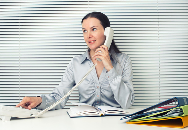 business woman sitting at office desk and talking on phone - Φωτογραφία, εικόνα
