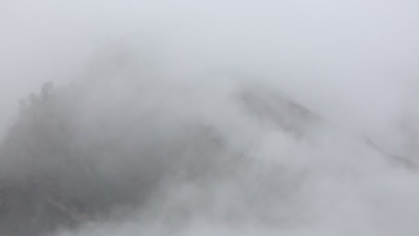 Rusland. In het vroege voorjaar pieken de dichte sluier van mist en wolken kruipend de steile berghellingen van de centrale Kaukasus. - Video