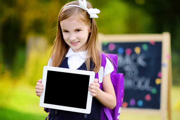 Little schoolgirl holding digital tablet - Foto, Imagen