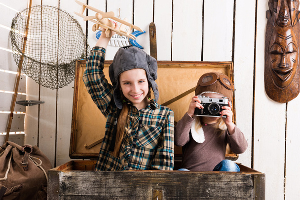 cute little girl taking photo of another little girl in wooden chest - Фото, зображення