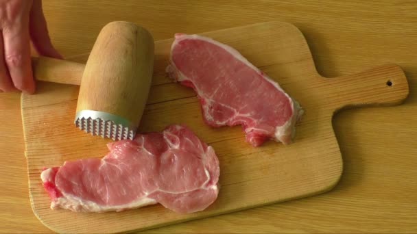 Tenderizzazione di bistecche fresche di maiale su tagliere di legno
 - Filmati, video