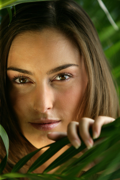 Mysterious woman hiding behind a fern - Foto, afbeelding