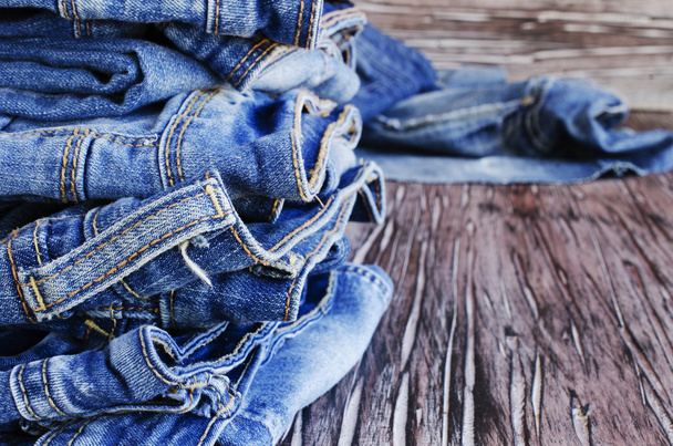 Стопка джинсов лежит на деревянном столе
 - Фото, изображение