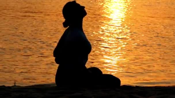 Tyttö käytännössä Lotos Pose rannalla auringonlaskun aikaan
. - Materiaali, video