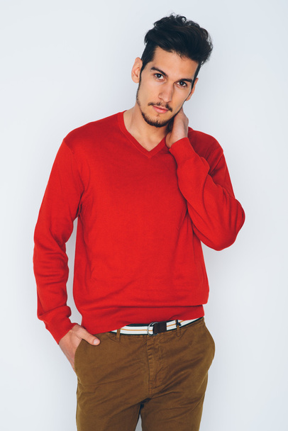 Young handsome man in red sweater and brown trousers - Photo, Image