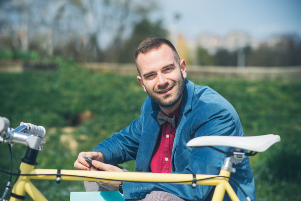 Nuori komea mies polkupyörän kanssa viettää aikaa ulkona
 - Valokuva, kuva