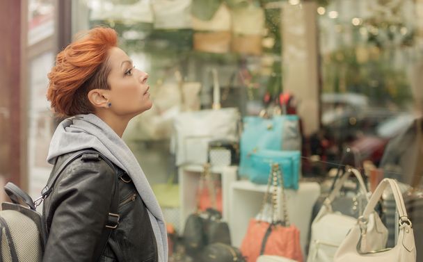 Woman looking in a shop window with handbags - Fotoğraf, Görsel