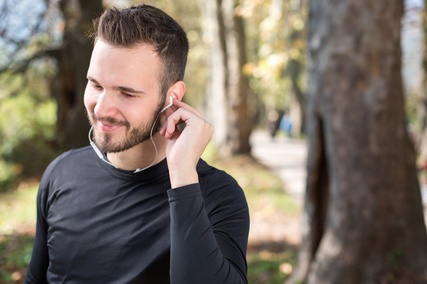 Portrait of handsome young man listening to music after running. - Photo, image