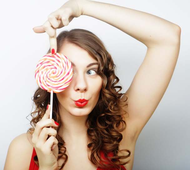 smiling cute girl covering her eye with lollipop over white back - Foto, immagini
