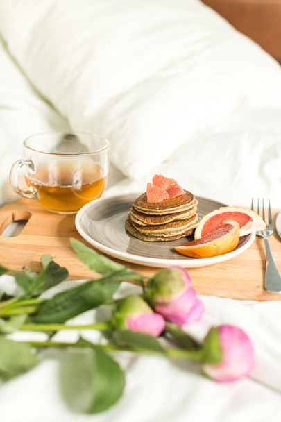 Breakfast in bed, Oatmeal pancakes with grapefruit, tea and Peon - Photo, Image