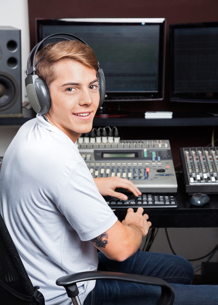 Smiling Young Man Mixing Audio In Recording Studio - Foto, afbeelding