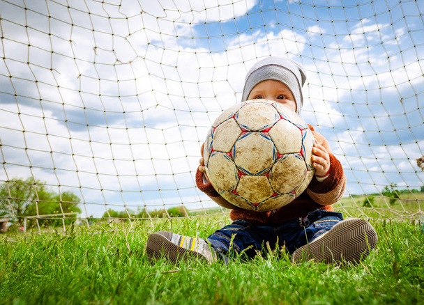 Ребенок в кепке играет с мячом
 - Фото, изображение