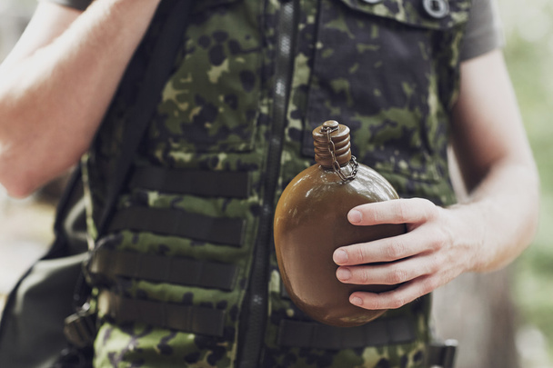 close up of soldier with gun and flask in forest - Фото, изображение