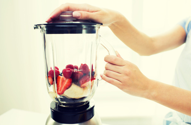 close up of woman with blender making fruit shake - Фото, изображение