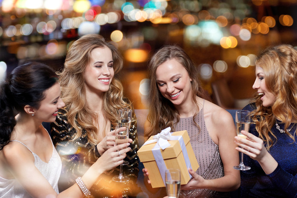 happy women with champagne and gift at night club - Фото, изображение