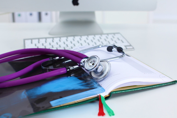 Stethoscope lying on a notebook computer in the background and books - Photo, Image