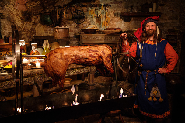 Middeleeuwse man doen geroosterde varken  - Foto, afbeelding