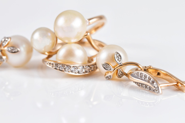 Elegante gouden ringen en gouden oorbellen met parels - Foto, afbeelding
