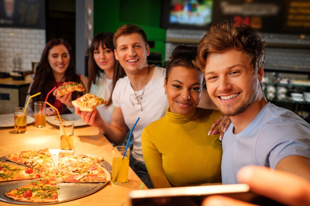 multiracial friends having fun eating pizza in pizzeria. - Foto, Imagen