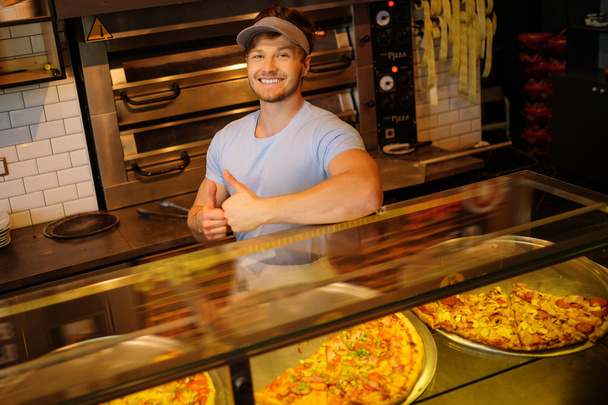 schöner Pizzaiolo steht in der Küche einer Pizzeria. - Foto, Bild