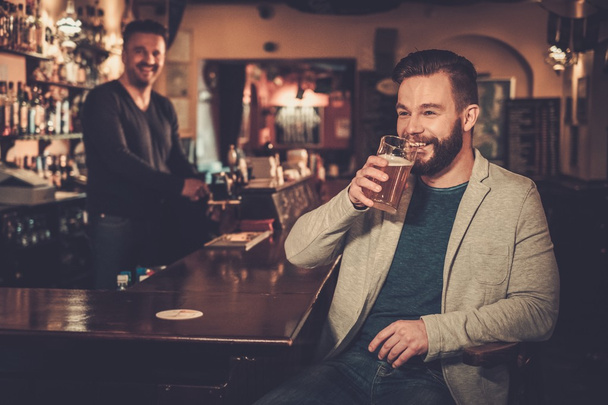 Tyylikäs mies maksaa oluen käteisellä euro baarimikko pubissa
.  - Valokuva, kuva