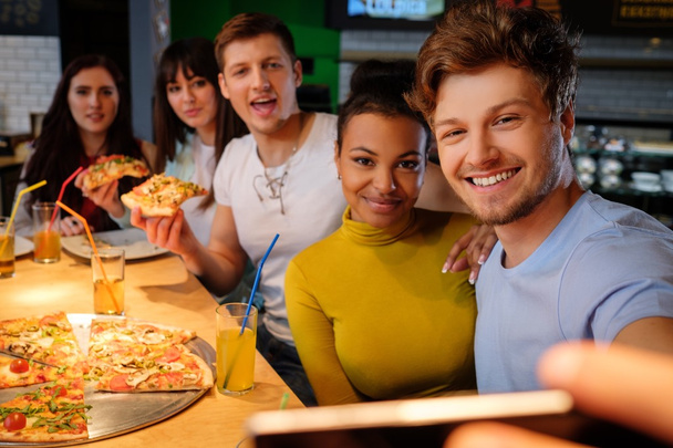 amigos multirraciales divirtiéndose comiendo pizza en la pizzería
. - Foto, imagen
