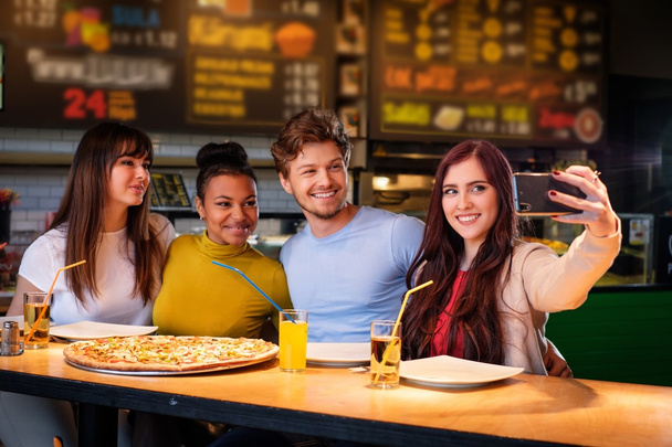 multiracial friends having fun eating pizza in pizzeria. - Photo, image
