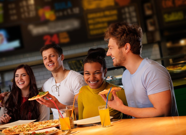 multirassische Freunde haben Spaß beim Pizza essen in der Pizzeria. - Foto, Bild