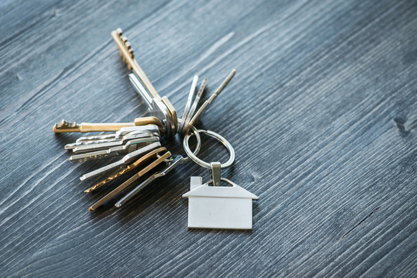 Mazzo di chiavi con portachiavi a forma di casa su un tavolo di legno
 - Foto, immagini