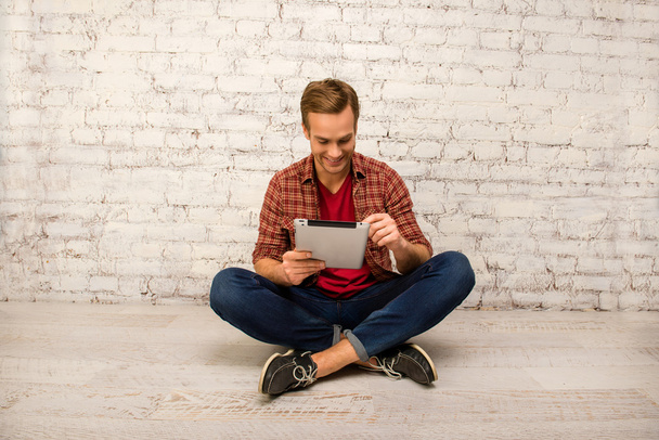 Happy man sitting on floor with crossed legs and tablet - Foto, Imagem