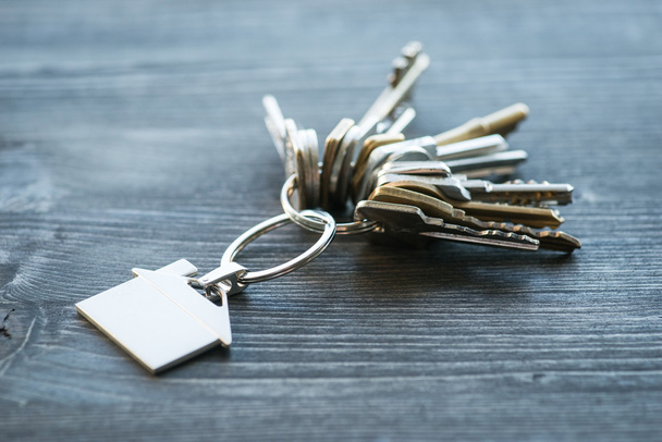 Pęk kluczy z domu w kształcie breloczek na drewnianym stole - Zdjęcie, obraz