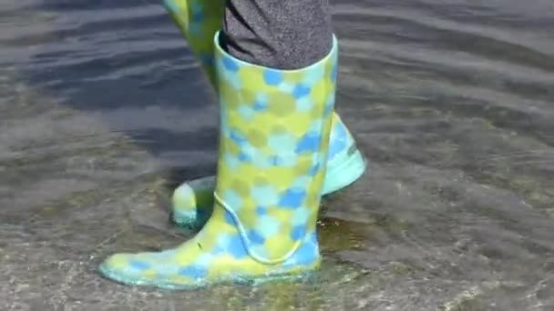 Дівчина перевіряє зелені гумові чоботи у воді. Повільний рух
. - Кадри, відео