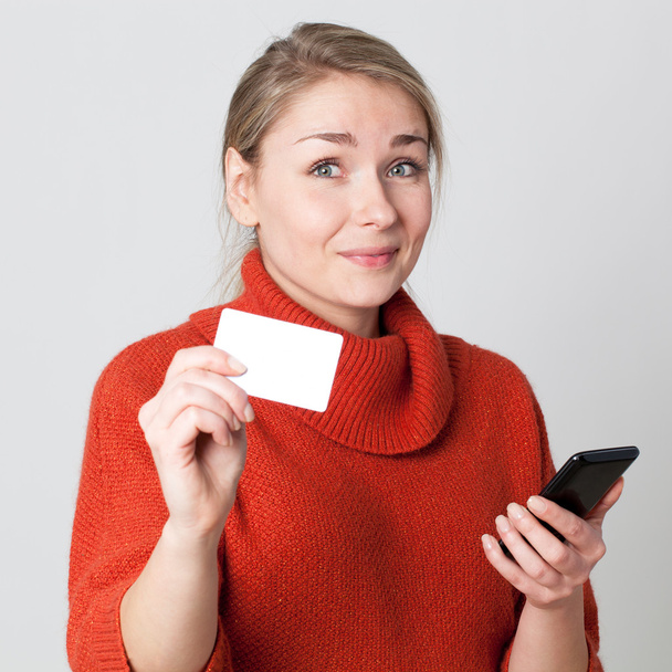unsure young blond woman buying on cell phone with copy space credit card for modern convenience - Foto, Imagem