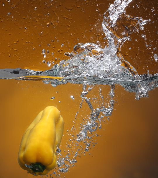 Pepe giallo che cade in acqua. Sfondo con lo stesso tono
 - Foto, immagini