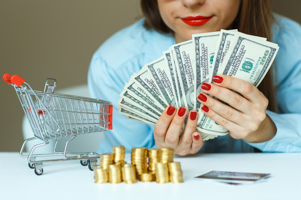 Woman holding cash, and on the table are coins, credit card and  - Photo, Image