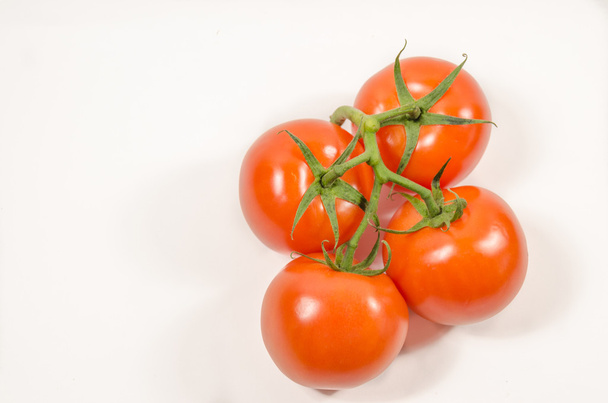 Вид зверху з чотирьох барвистих помідорів на лозі на білому тлі
 - Фото, зображення