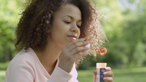 Young beautiful afro hair woman blowing soap bubbles, outdoor. - Filmati, video