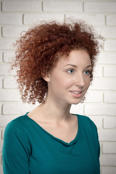 portrait of beautiful ginger curly woman model against brick wall - Foto, Imagen