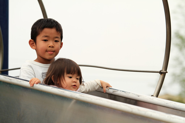 Japanese brother and sister on the slide (6 years old boy and 1 year old girl) - Photo, Image