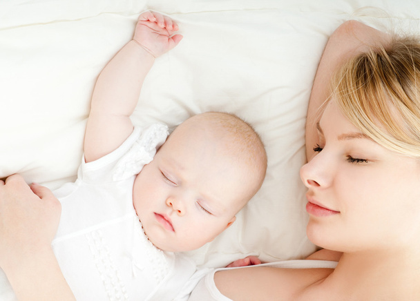 junge Mutter und ihr Baby schlafen im Bett - Foto, Bild
