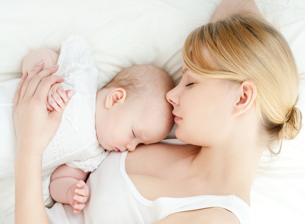 Young mother and her baby sleeping in bed - Фото, зображення