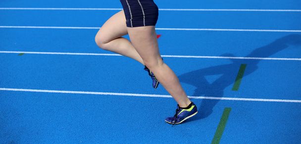 μακριά πόδια νεαρό θηλυκό δρομέας τρέχει στο αθλητικό προσκήνιο - Φωτογραφία, εικόνα