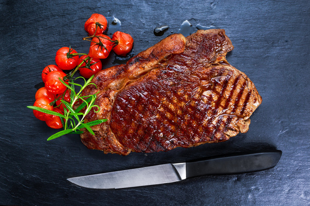 Carne alla griglia Sirloin Steak su sfondo di pietra blu, con verdure
. - Foto, immagini
