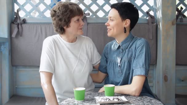 Senior mother and young daughter talking on sofa, laughing and having coffee together. Happy family. - Záběry, video