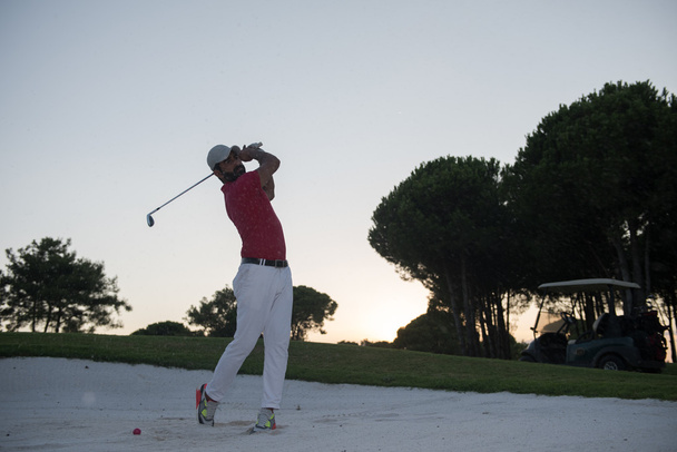 砂の燃料庫を打つゴルファーが夕日で撮影 - 写真・画像