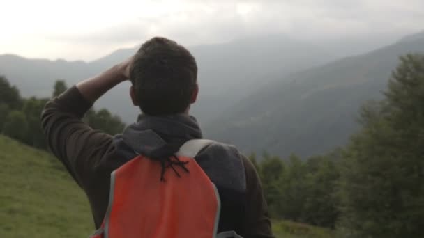 Young man with a red vintage backpack is walking outdoor on mountain path - Felvétel, videó