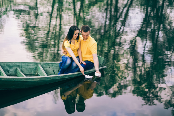 Young girl and man sitting together in old wooden boat on river. - Photo, Image