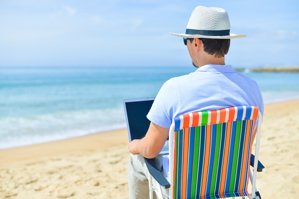 島の美しい白砂のビーチの休暇のラップトップを持つ男の背面図 - 写真・画像