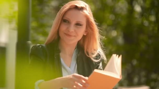 Young beautiful blonde girl in summer day is reading a book  - Video, Çekim